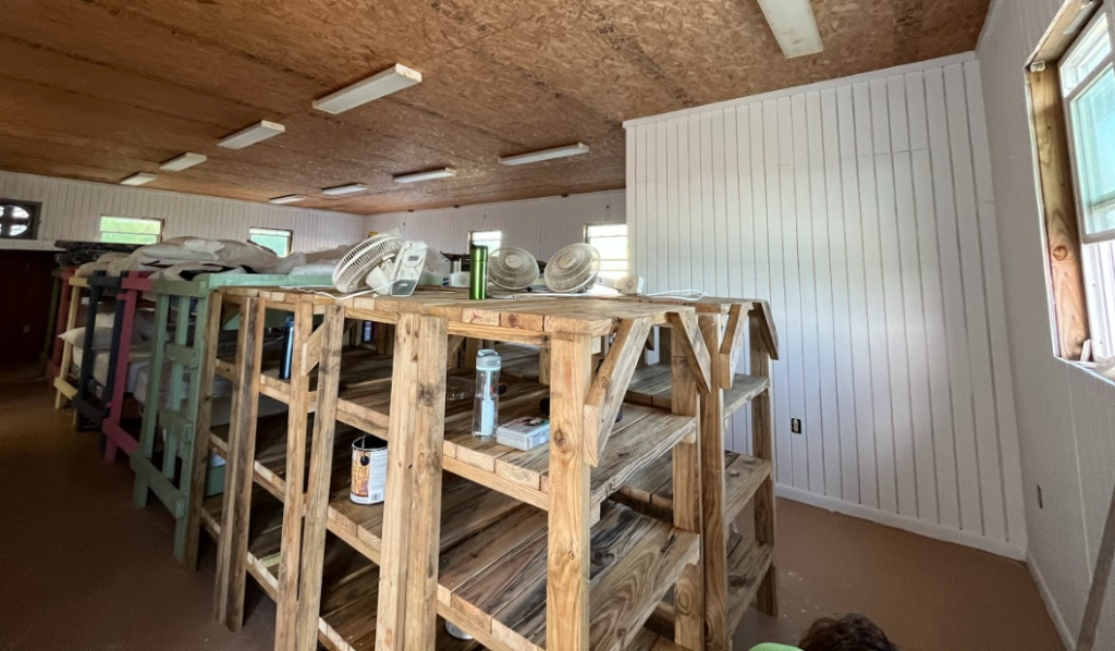 Wooden bunk beds in an open room with freshly painted white walls