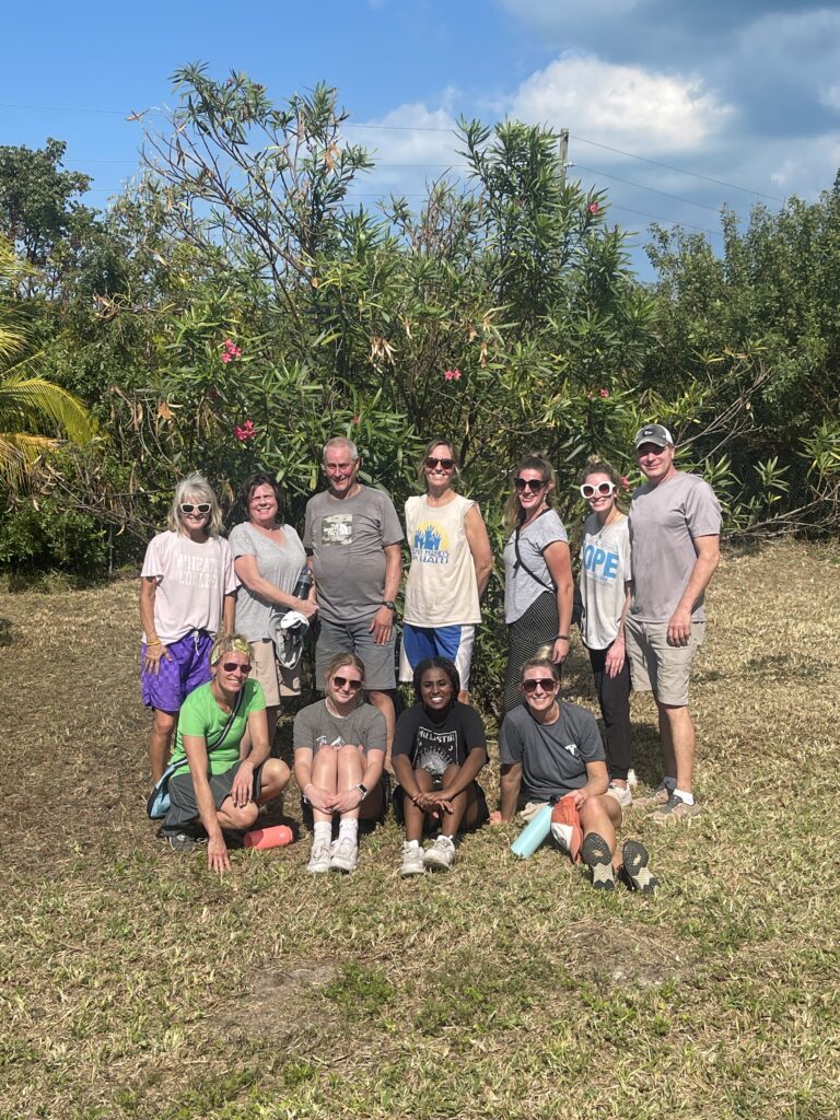 Michigan team of 11 standing in front of tropical trees