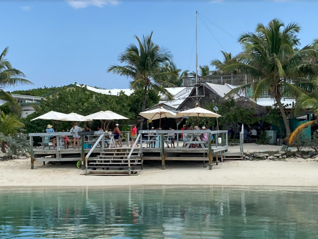 Lifted deck next to the water with covered tables for people to eat on