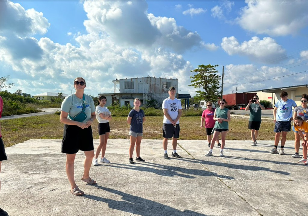 Team members standing on a concrete slab, listening to the speaker give a tour of the town