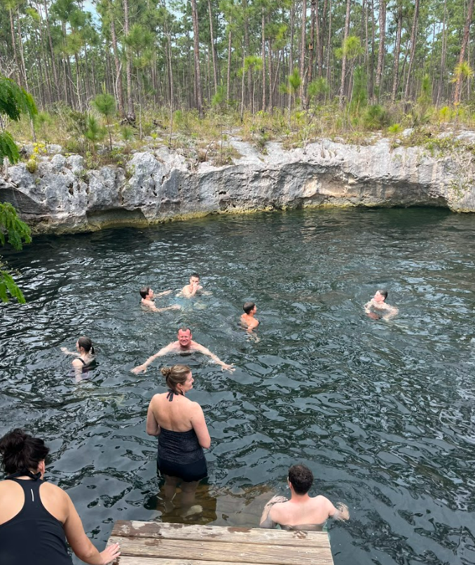 The team swimming in the blue hole, which looks like a small pond