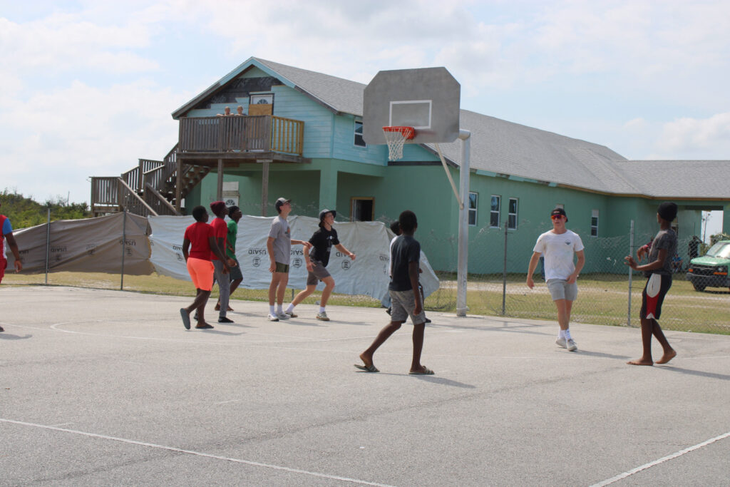 Team members and community members play a quick game of basketball.