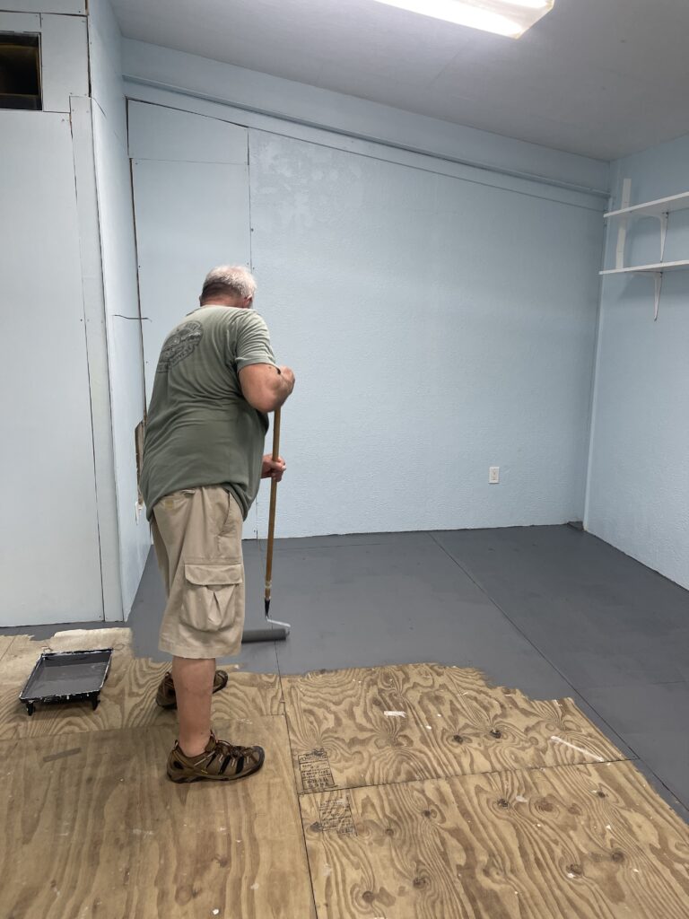 Team member paints the floor gray in Agape school gym