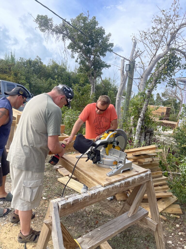 Three men cutting treated wood for bunk beds outside